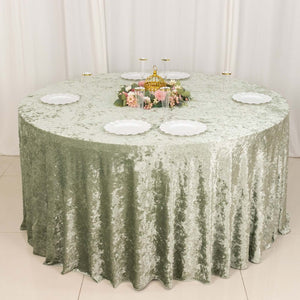 Round green velvet tablecloth with white plates and floral centerpiece.