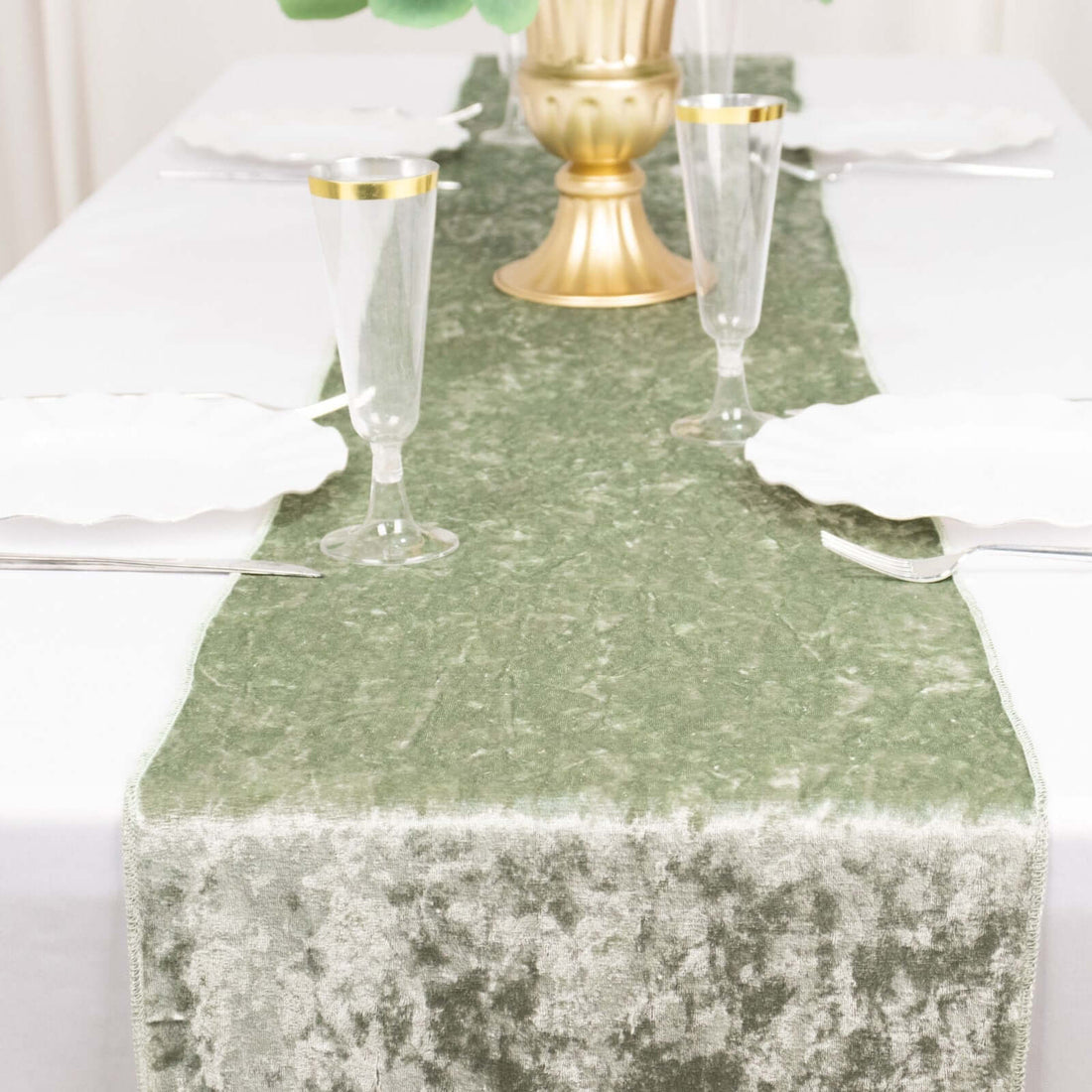 Elegant green table runner on a white dining table setting with glassware.