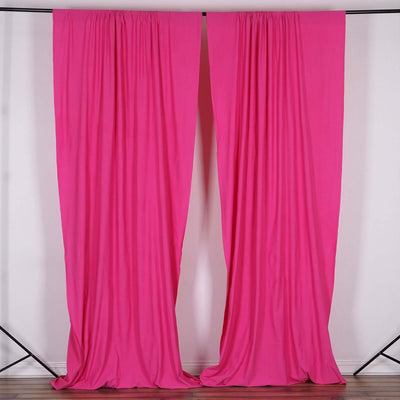 Pink drapery curtains hanging from a black stand.