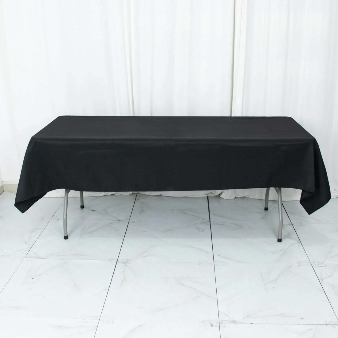 Black tablecloth draped over a rectangular table in a studio setting.