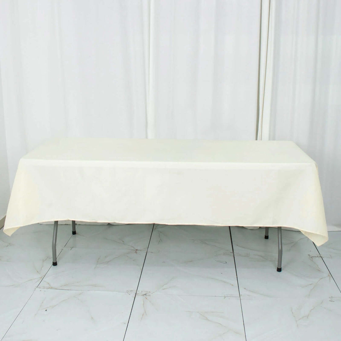 Cream tablecloth draped over a folding table in a studio setting.