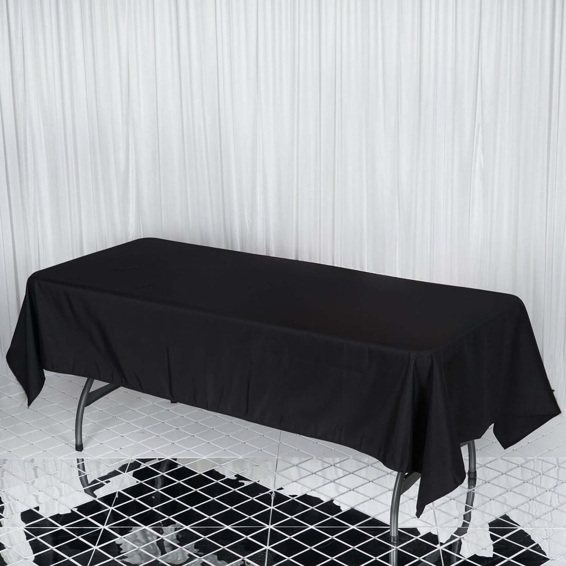 Black tablecloth draping over a rectangular table in a studio setting.