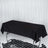 Black tablecloth draping over a rectangular table in a studio setting.