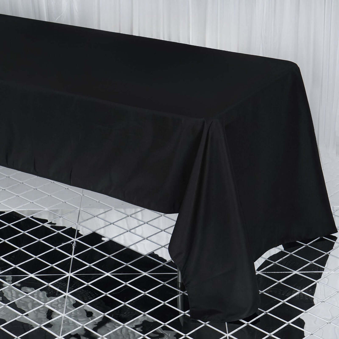 Black tablecloth draped over a table on a reflective surface.