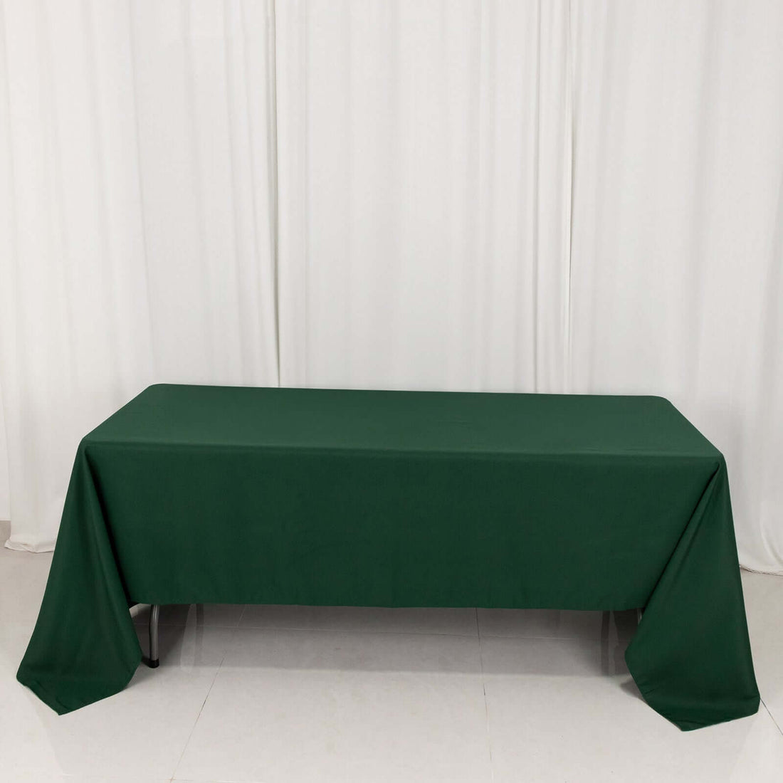 Green tablecloth draped over a table against a plain backdrop.