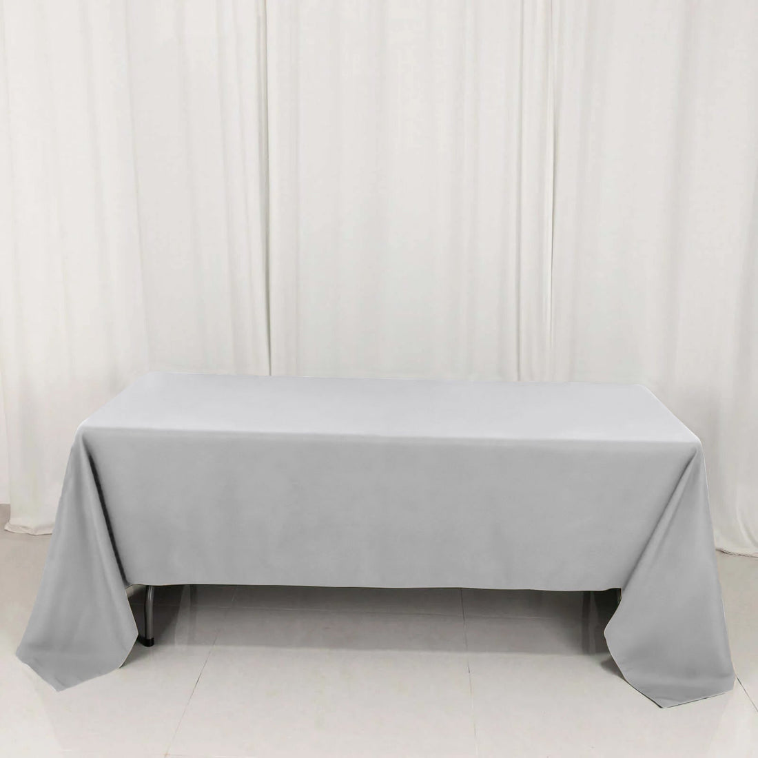 Gray tablecloth on a table with white drapes in the background.