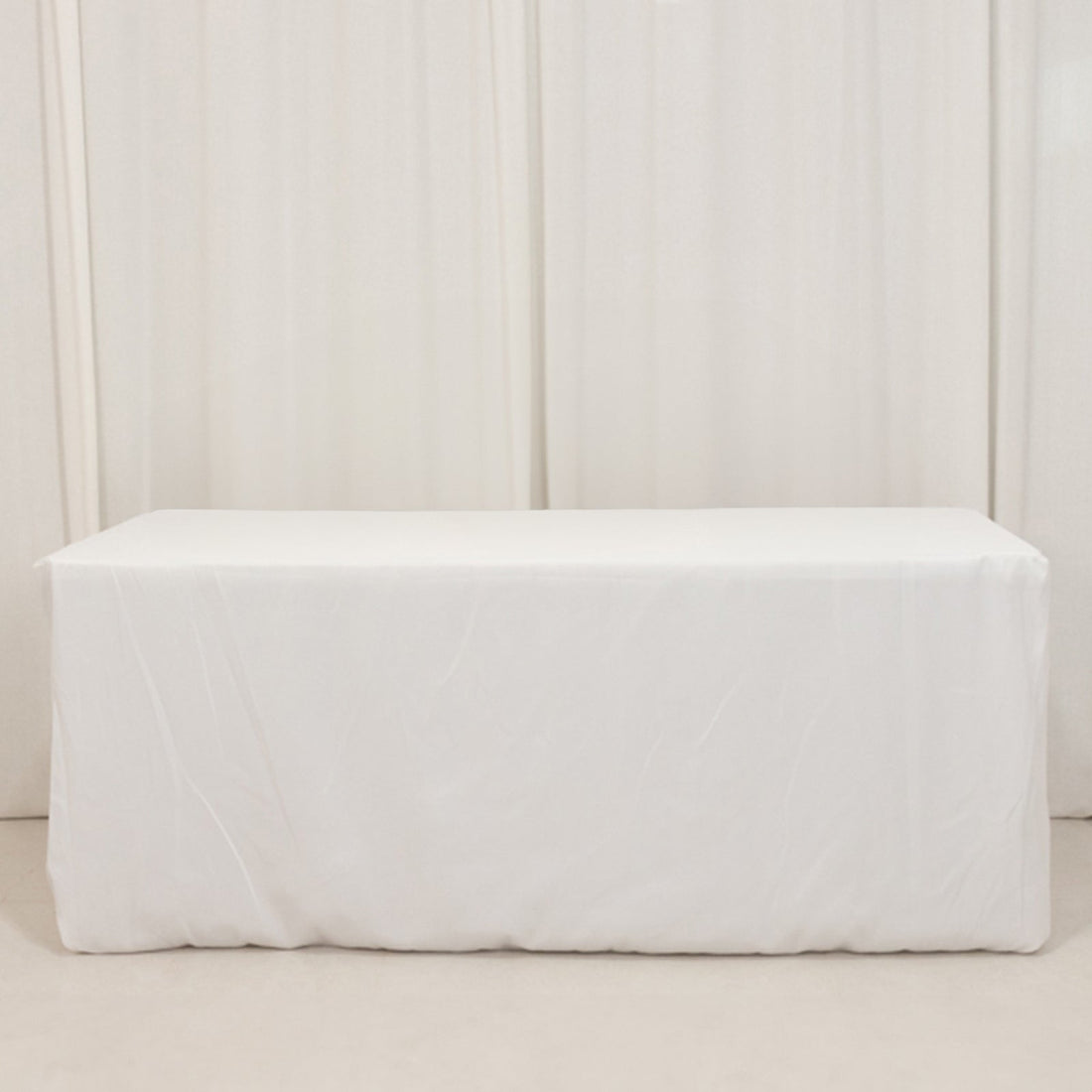 White table covered with a plain tablecloth in a studio setting.