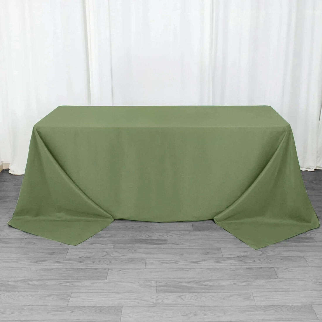 Green tablecloth draped over a table on a wooden floor.