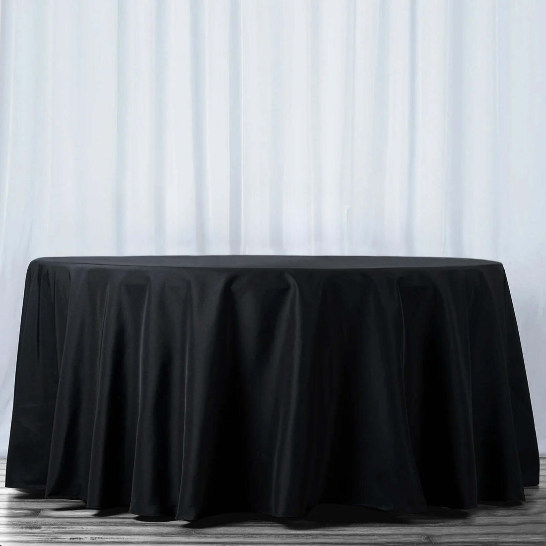 Black round tablecloth on a table against a soft white background.