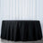 Black round tablecloth on a table against a soft white background.