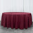 Round burgundy tablecloth on a wooden floor.
