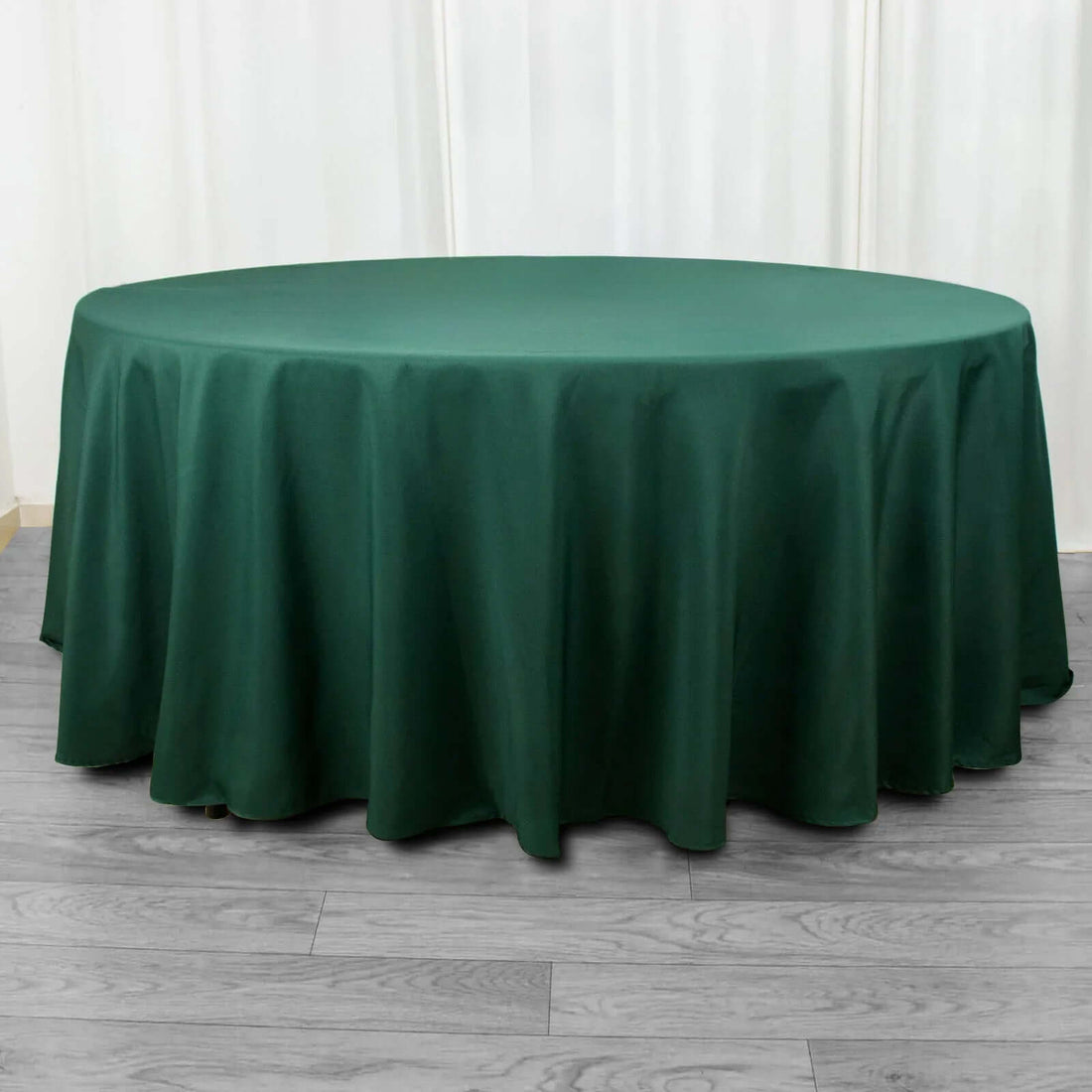 Green round tablecloth on a wooden floor.