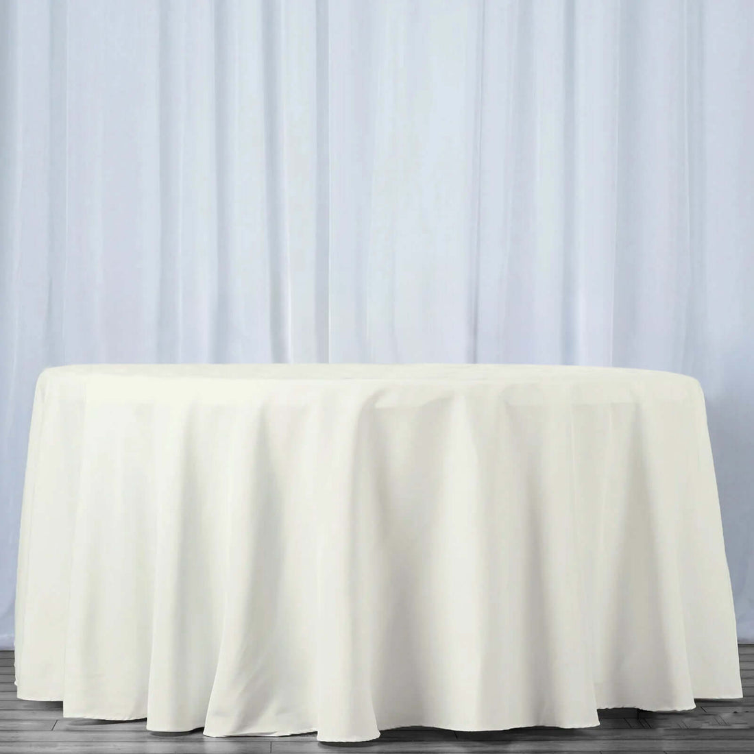 White tablecloth draped over a round table against a light backdrop.