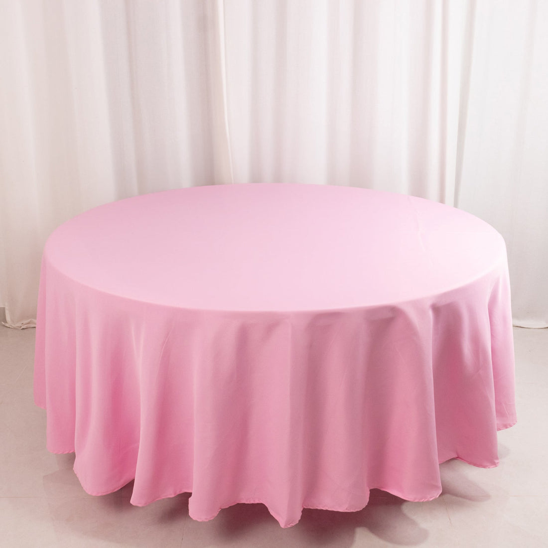 Round pink tablecloth on a plain backdrop.