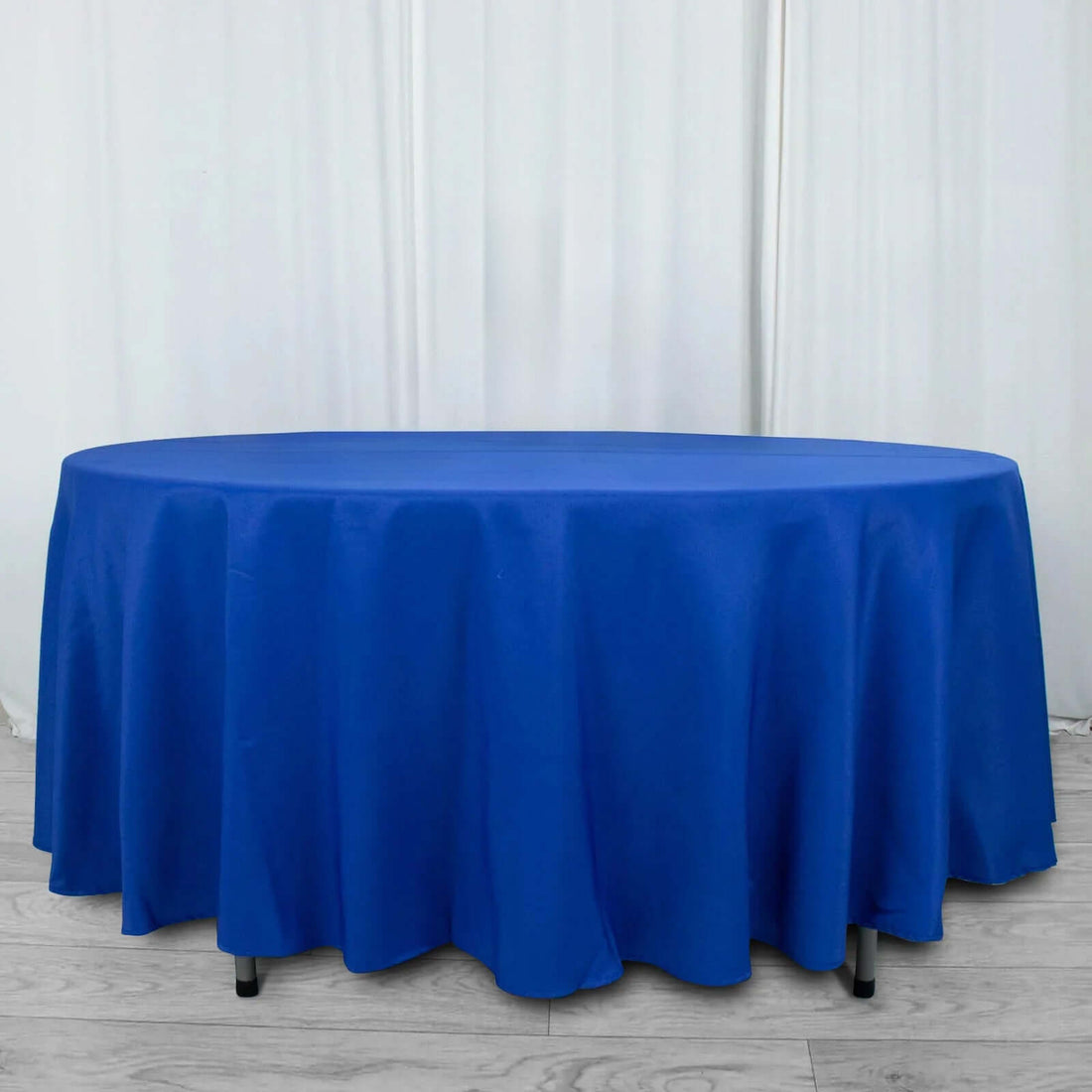 Round blue tablecloth draping over a table in a studio setting.