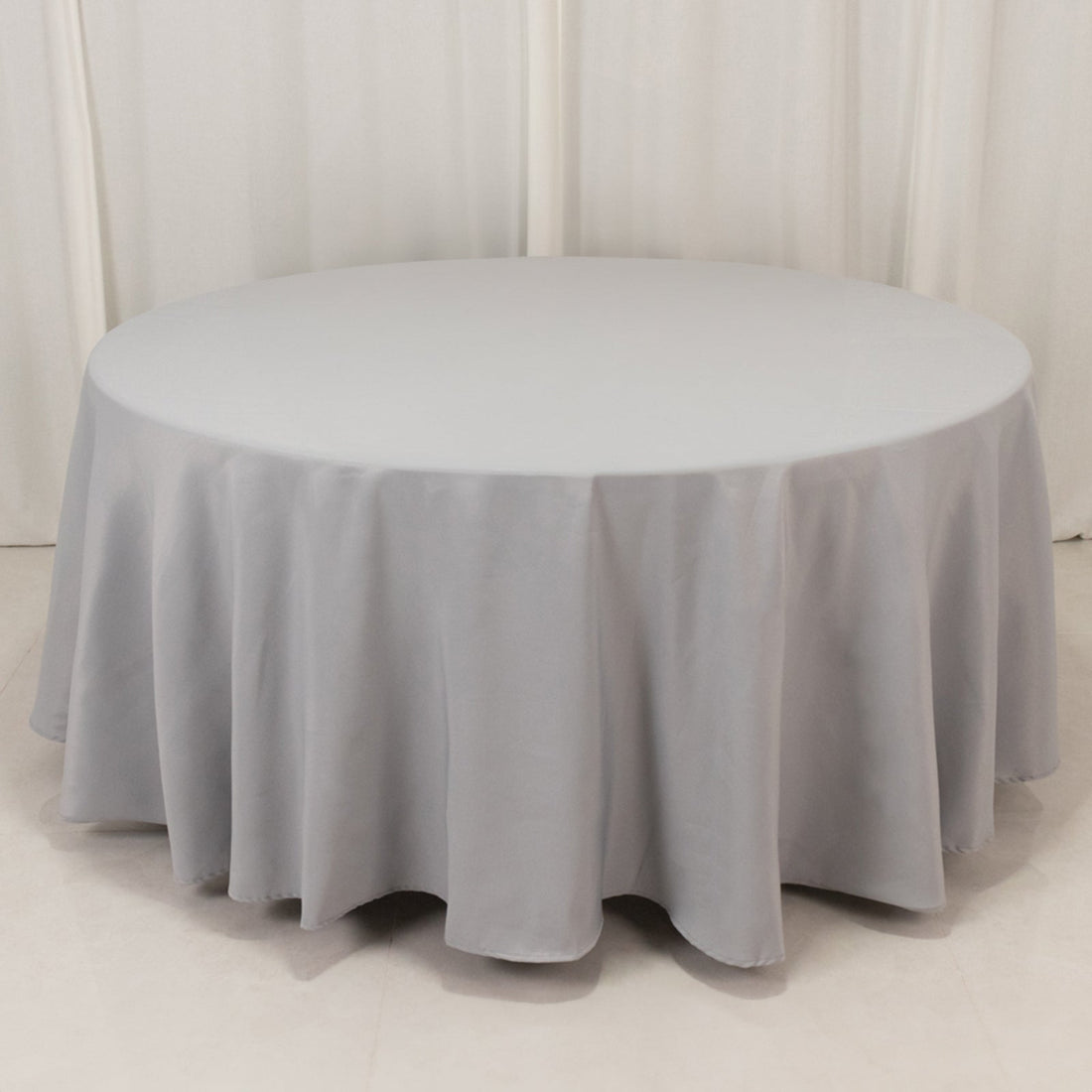 Round gray tablecloth draped over a circular table in a studio setting.