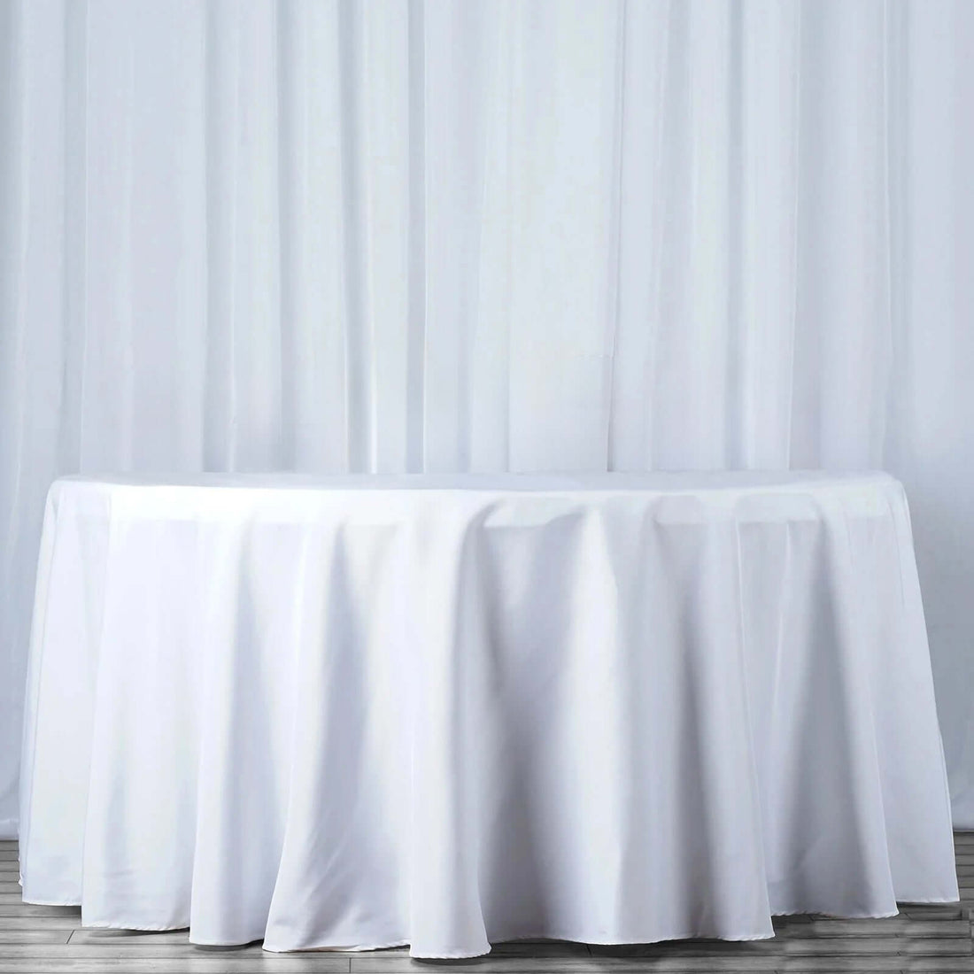 White tablecloth draped over a round table in a studio setting.