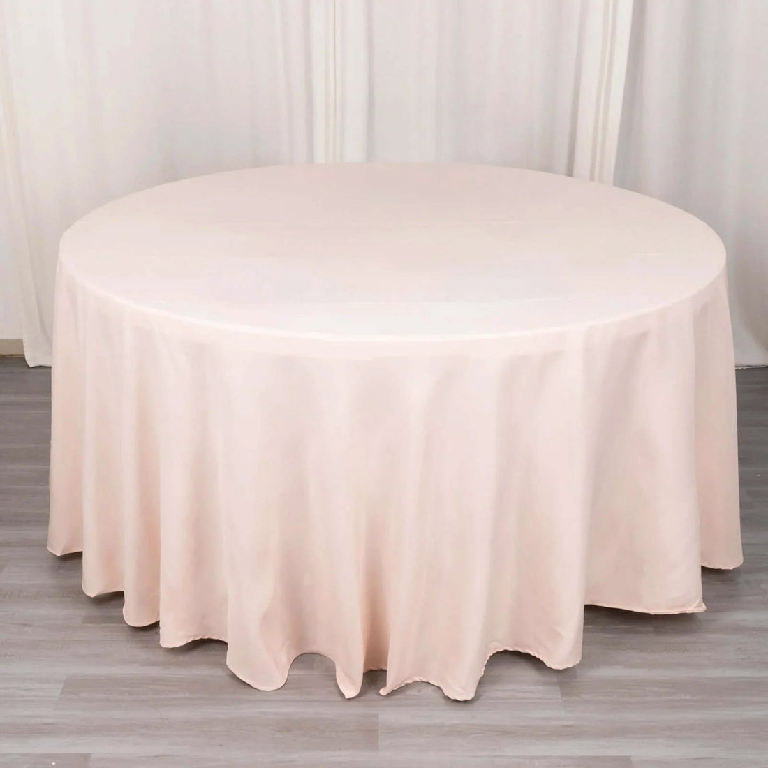 Round blush tablecloth on a table with draped edges.