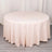 Round blush tablecloth on a table with draped edges.