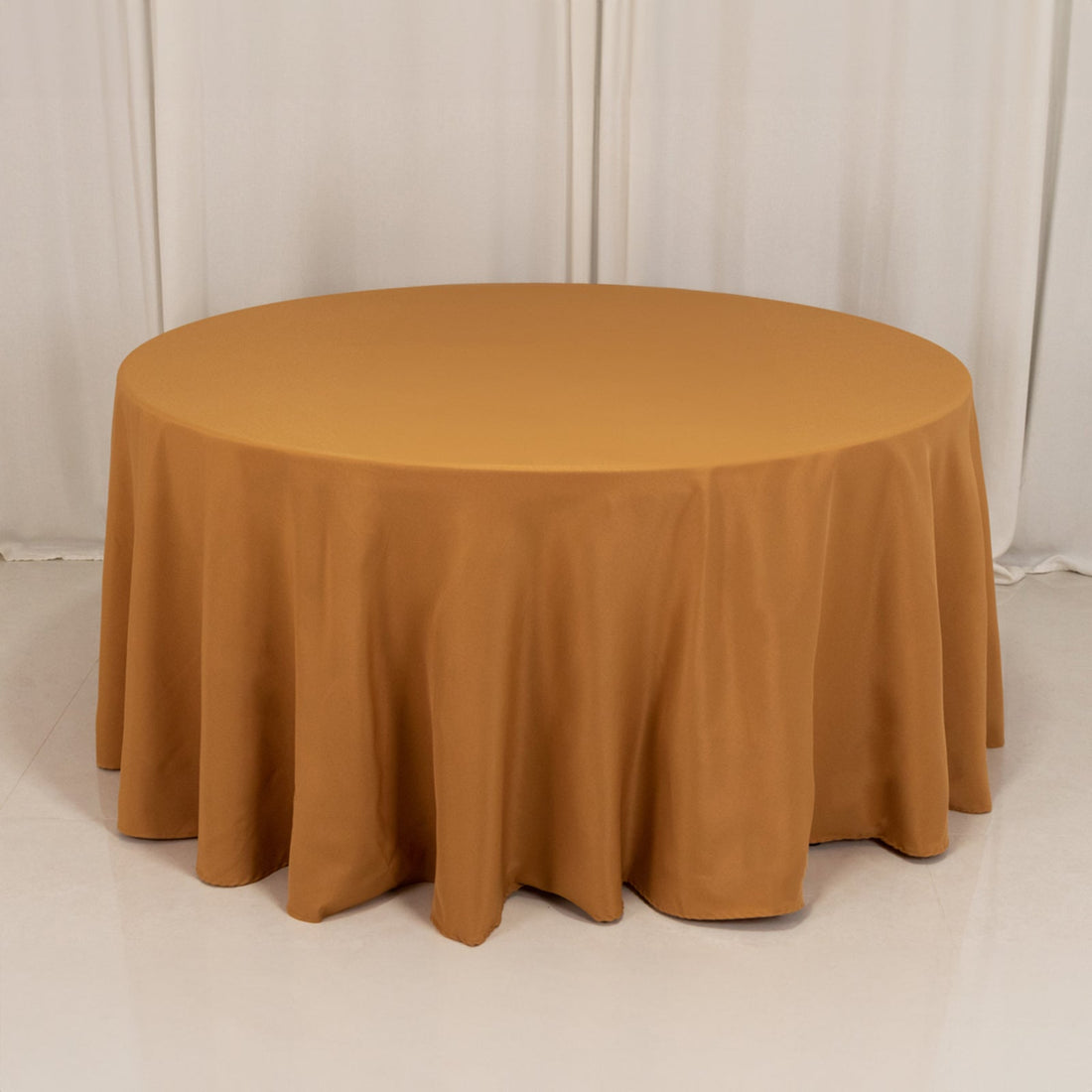 Round gold tablecloth draped elegantly over a circular table.