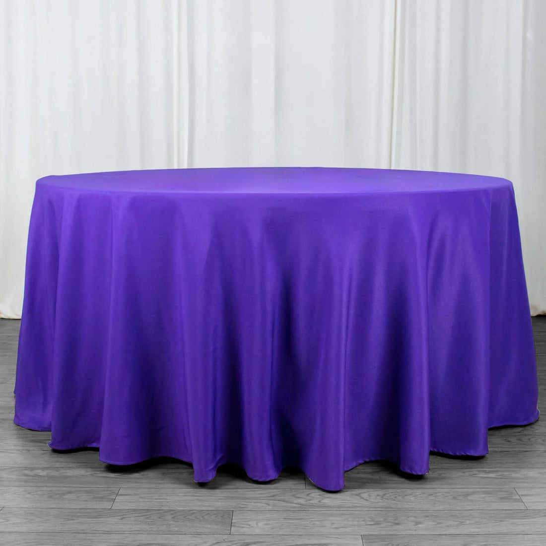Purple round tablecloth draped over a table in studio setting.