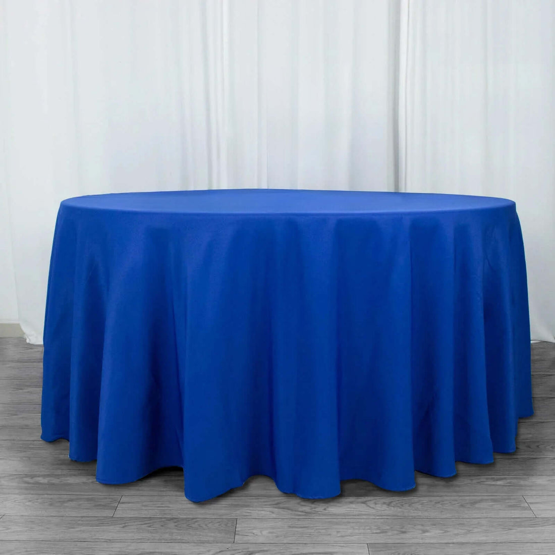 Round blue tablecloth on a wooden floor backdrop.