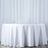 White tablecloth draped over a round table against a plain backdrop
