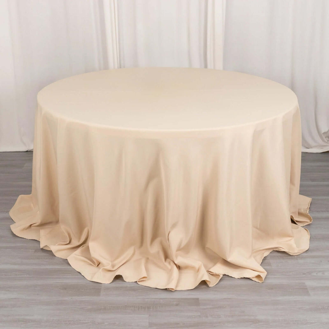 Round beige tablecloth draped elegantly on a circular table.