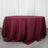 Burgundy tablecloth draped over a round table in a studio setting.