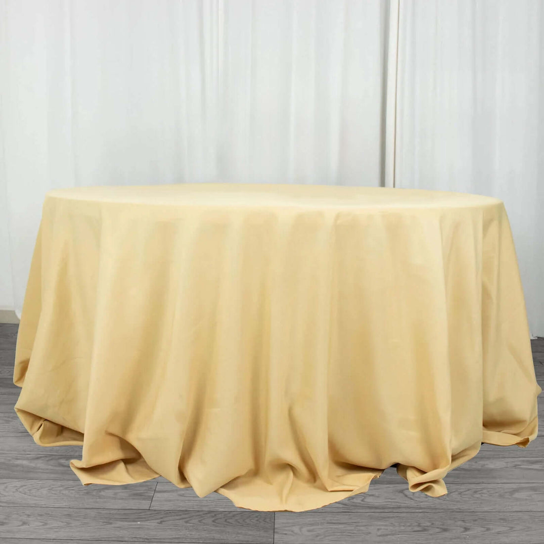 Round table covered with a beige tablecloth.
