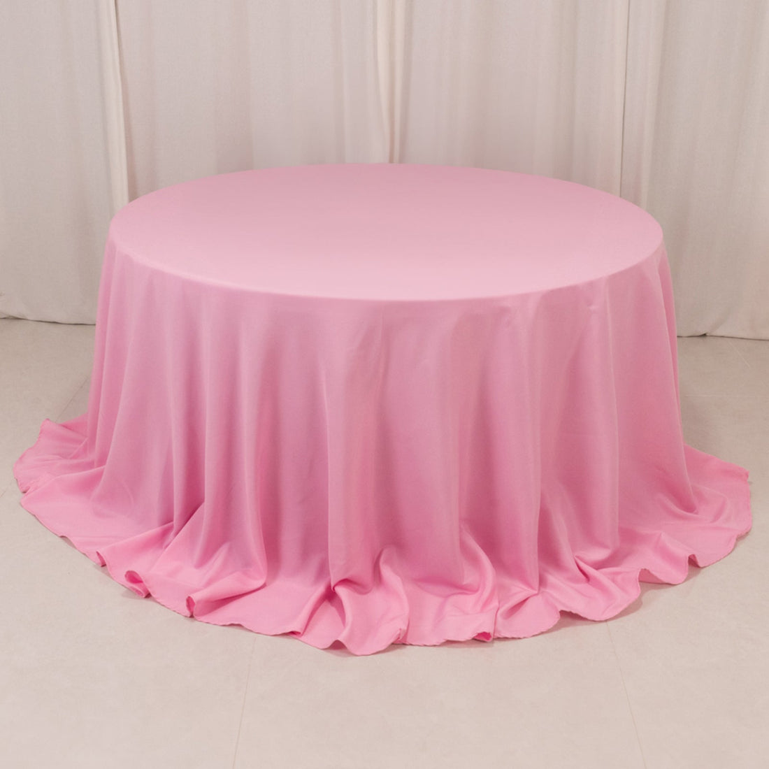 Round pink tablecloth with elegant draping.