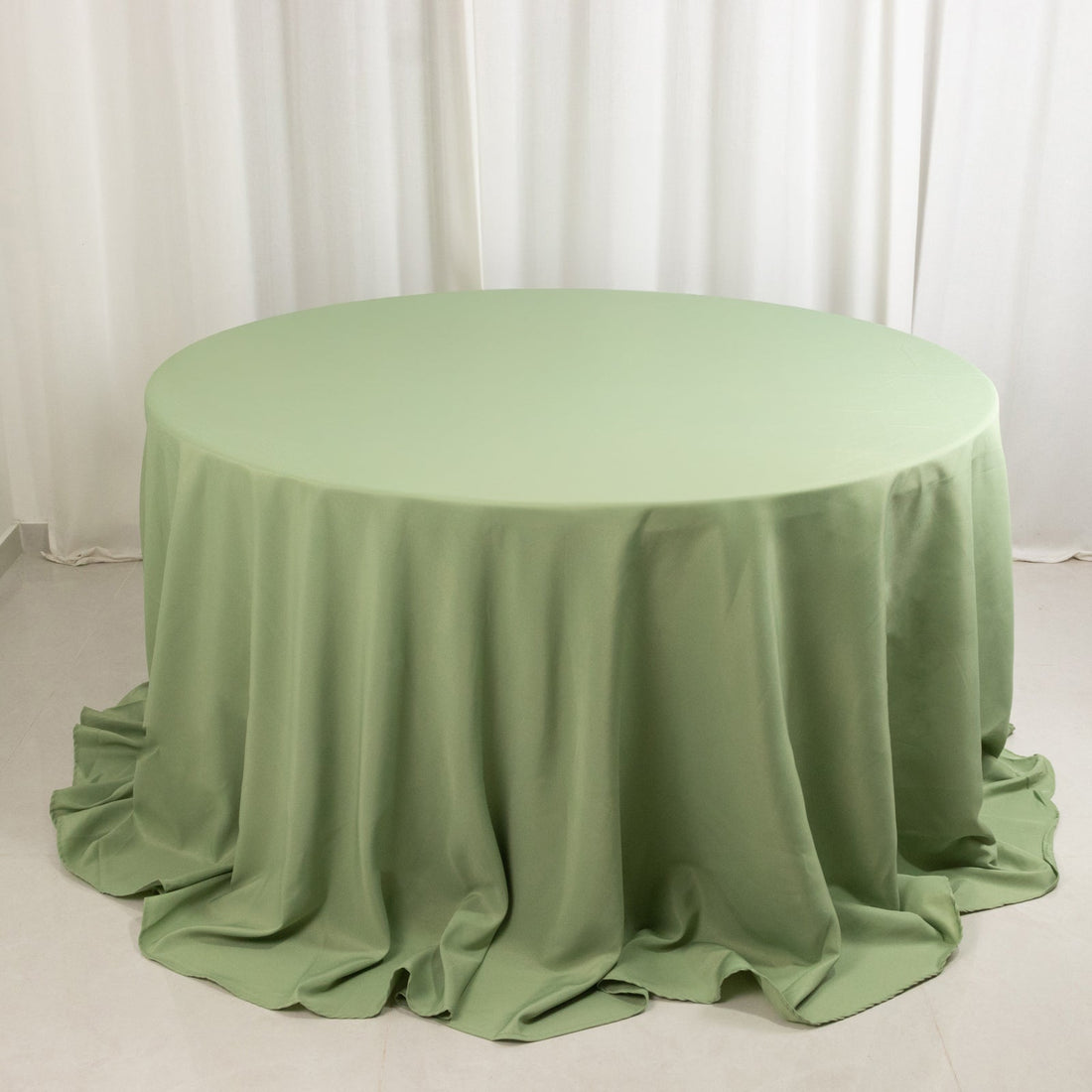 Round green tablecloth on a table with soft draping.
