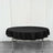 Round black tablecloth draped over a folding table against a plain backdrop.
