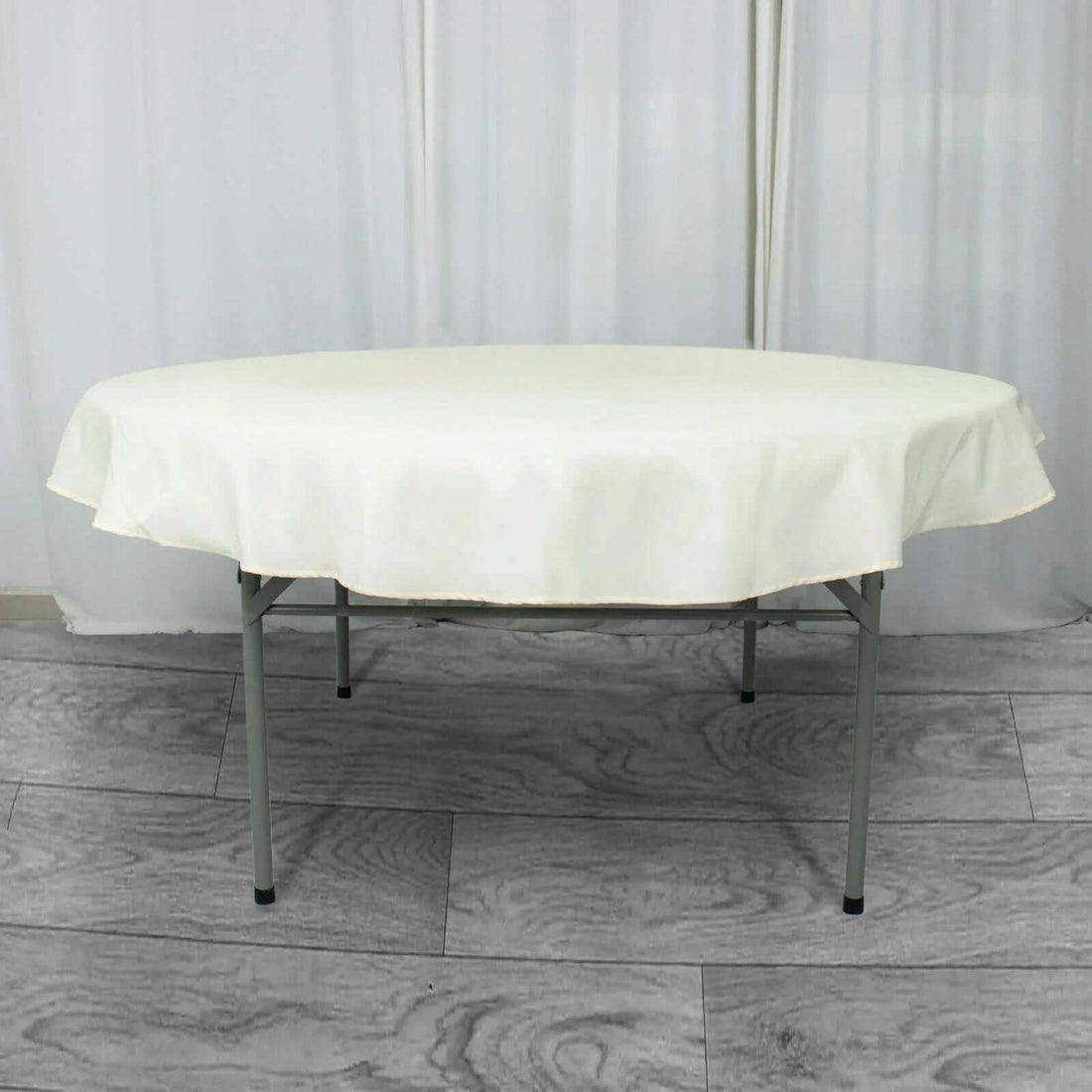 Round folding table with a cream-colored tablecloth.