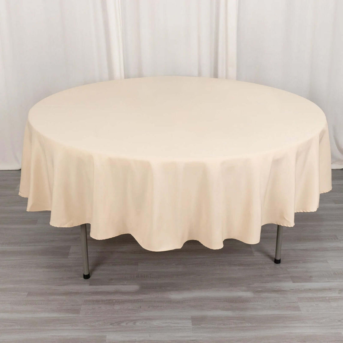 Round beige tablecloth draped over a table in a studio setting.
