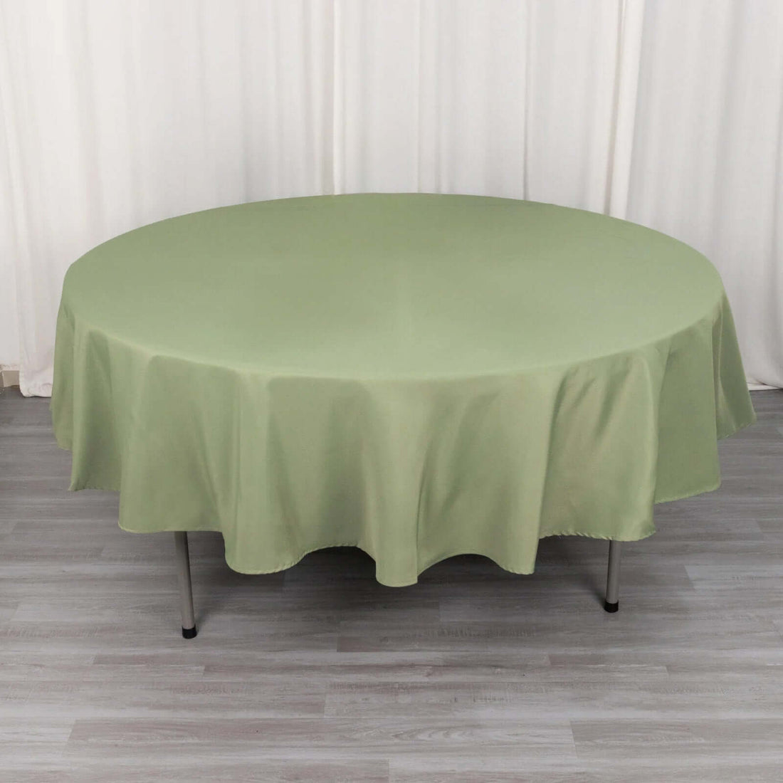 Round green tablecloth on a circular table with a smooth drape.