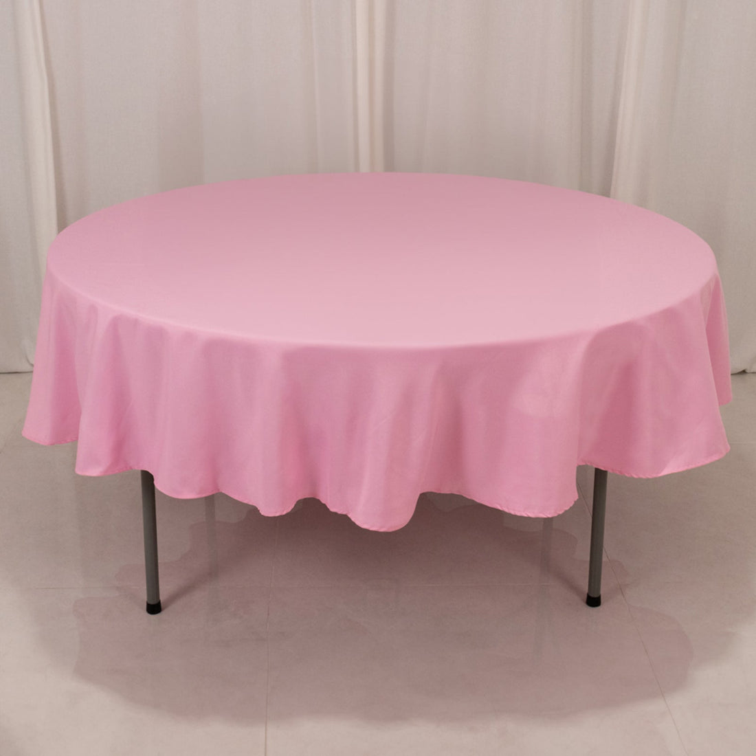 Pink round tablecloth on a folding table.