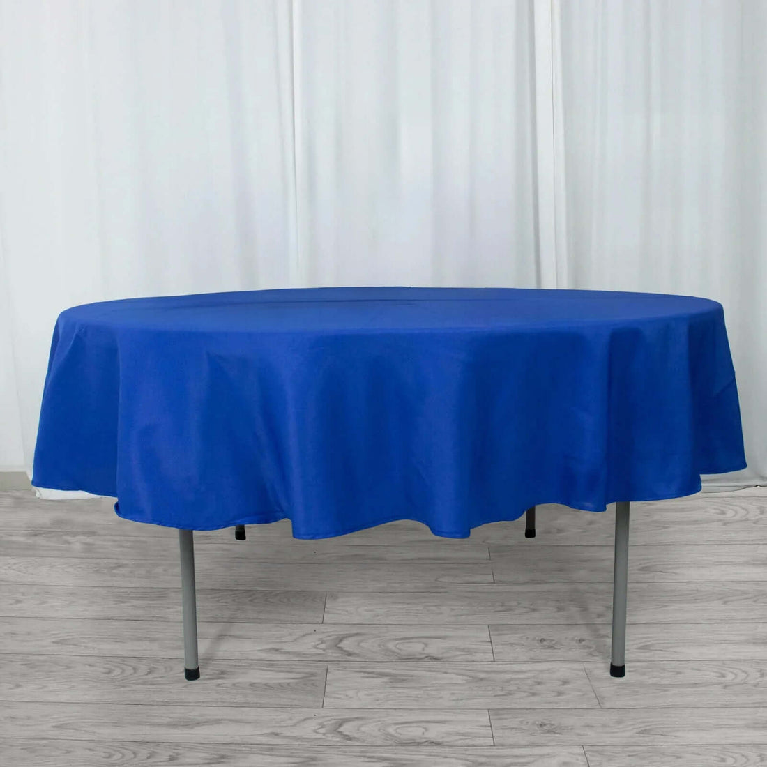 Round blue tablecloth draped over a table in a studio setting.