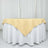 Yellow tablecloth draped over a round table with a white base.