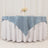 Blue tablecloth draped over a white round table with floral centerpiece.