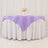 Purple tablecloth draped over a round table with floral centerpiece.