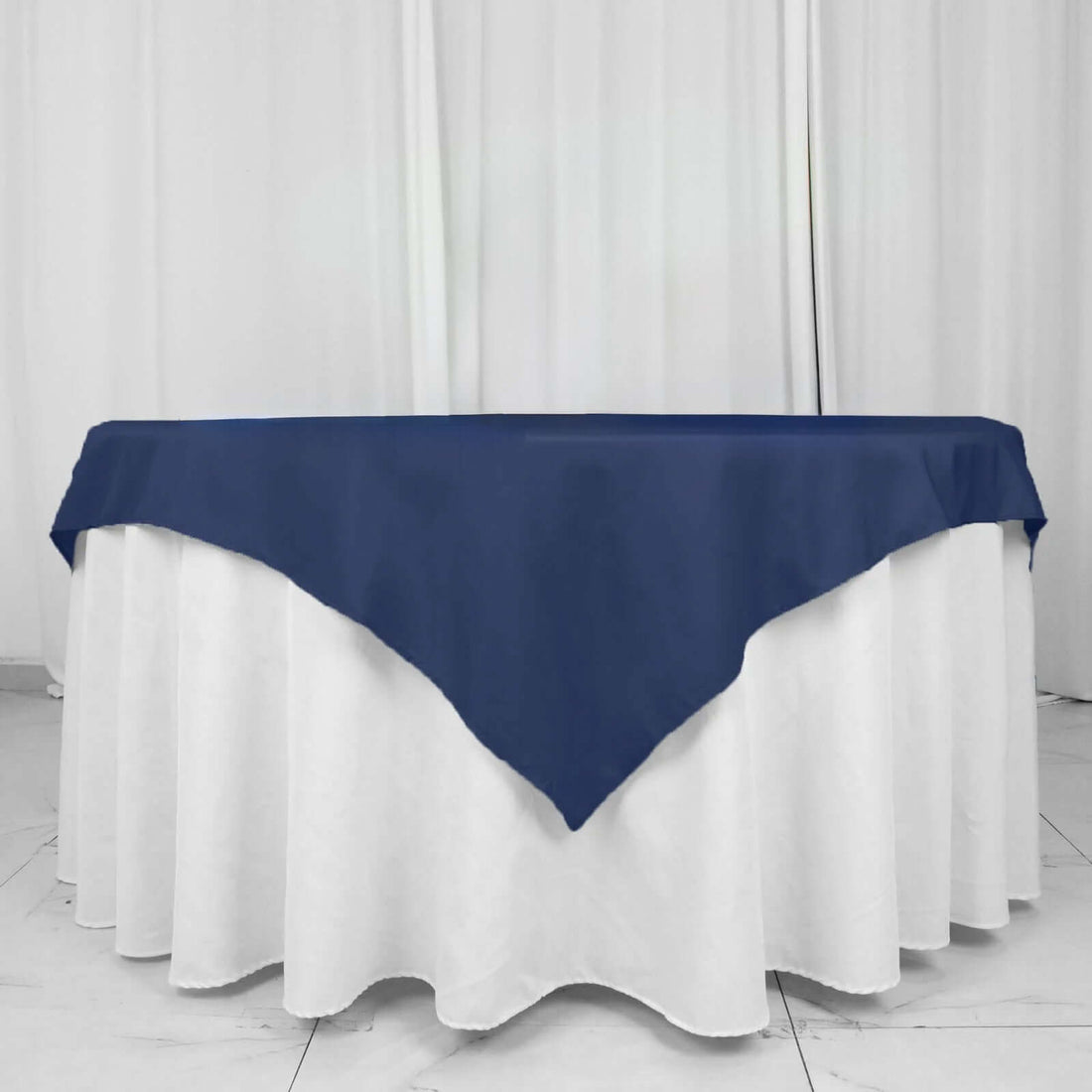 Navy tablecloth draped over a white table in a studio setting