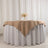Table set with a beige tablecloth and floral centerpiece on a white backdrop.