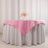 Pink tablecloth draped over a white table with floral centerpiece.