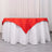 Red tablecloth draped over a white table in a studio setting.