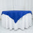 Blue tablecloth draped over a round table with white skirt.