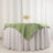 Green tablecloth draped over a round table with floral centerpiece.