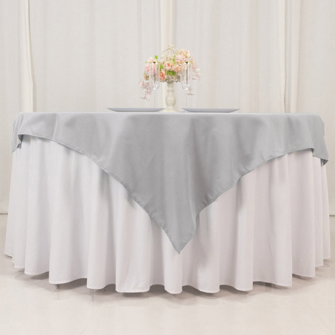 Gray table runner on a white tablecloth with floral centerpiece.