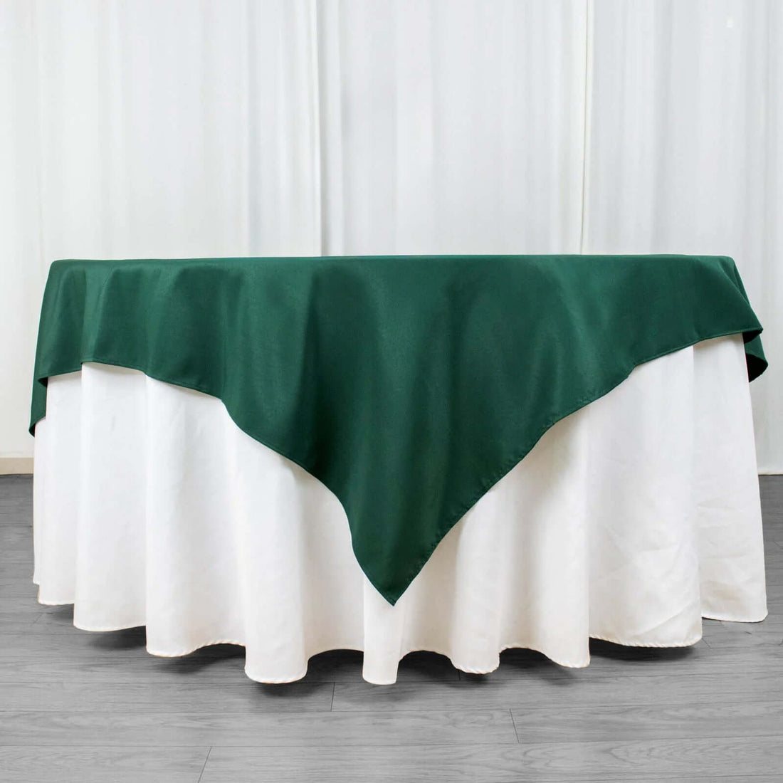 Green tablecloth draped over a white table with a pleated edge.