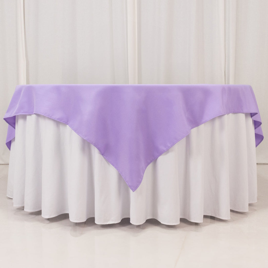 Purple tablecloth draped over a round table with a white skirt.